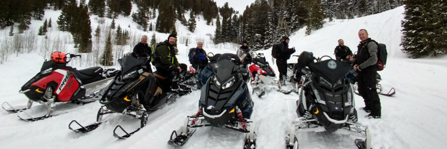 Snowmobile riders pausing for a lunch break while riding Poker Peak